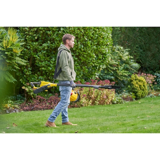 Photo of STANLEY SFMCPS720M1 pole saw carried by person in garden, yellow and black color.