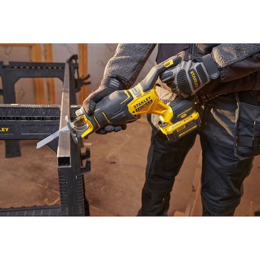 STANLEY SFMCS311B-XJ cordless reciprocating saw cutting metal, close-up of tool in use in workshop.