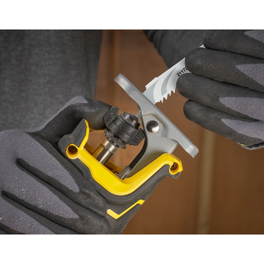 Photo of STANLEY SFMCS311B-XJ tool handle with blade being inserted, close-up, worker in gloves.