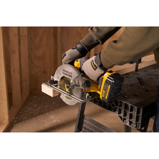 Photo of Stanley SFMCS500B circular saw cutting wood, close-up action, worker wearing gloves.