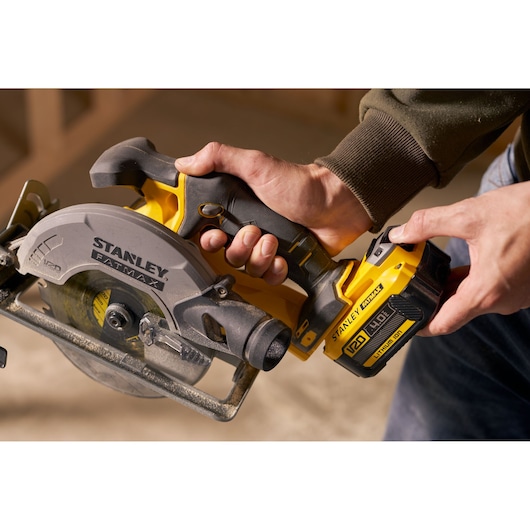 Stanley SFMCS500M1S circular saw held by hand, close-up angle, yellow and black photography.