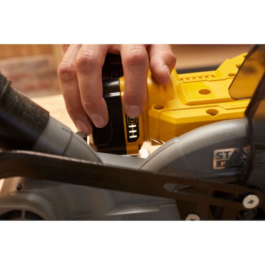 Close-up photo of hand inserting battery into STANLEY SFMCS701B power tool.