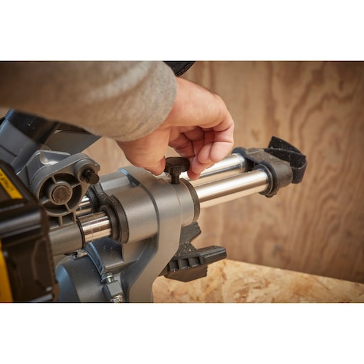 STANLEY SFMCS701M2 miter saw close-up, hand adjusting knob, silver rails, woodworking setup.
