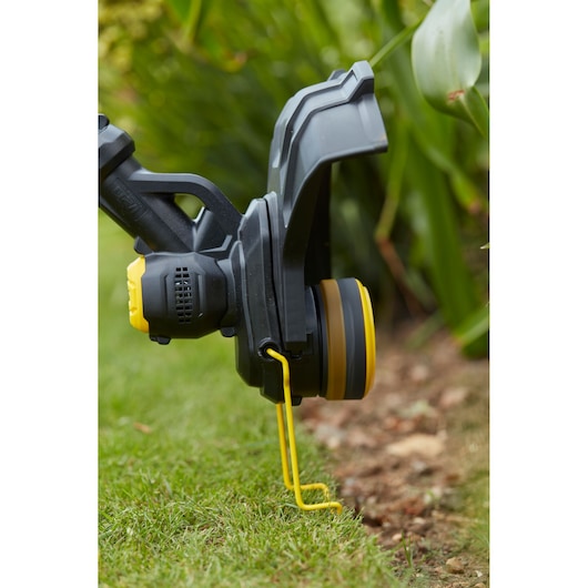 STANLEY SFMCST933B grass trimmer close-up photo showing the cutting head and yellow guard during lawn edging.
