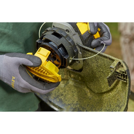Photo of STANLEY SFMCSTB963B string trimmer spool being installed, close-up outdoor view.