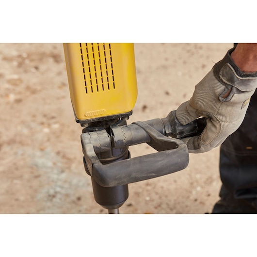 Photo of STANLEY SFMEH230K-QS hammer drill handle held by gloved hand, outdoor close-up.