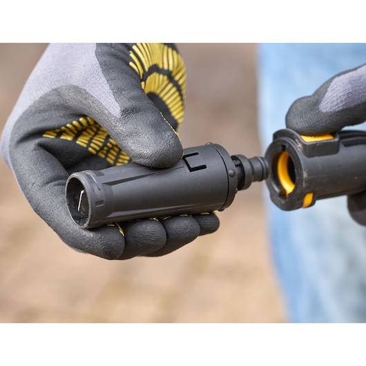 Photo of STANLEY SFMPW1740 pressure washer nozzle held by gloved hands, close-up angle.