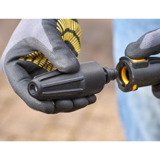 STANLEY SFMPW2000 pressure washer nozzle held by gloved hands, close-up angle.