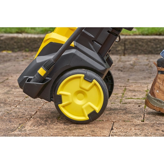 STANLEY SFMPW2000 yellow and black pressure washer wheel close-up, outdoor paving surface