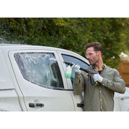 STANLEY SFMPW2400 pressure washer spraying soap on white car exterior, outdoor photography.