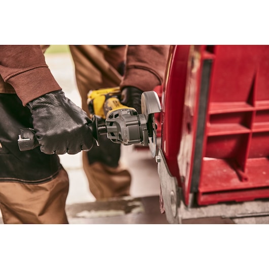 STANLEY STA32637 angle grinder in use cutting red metal, close-up showing gloved hands operating tool.