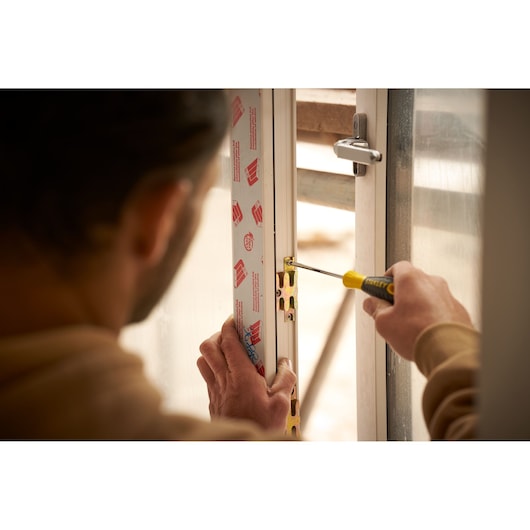 STANLEY STHT0-60276 screwdriver used to install a metal latch in a door frame, close-up photography.