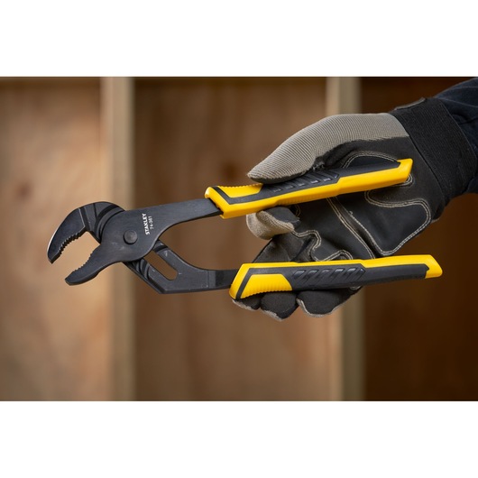 Photo of STANLEY STHT0-74361 adjustable pliers with yellow and black handles, held by a gloved hand.