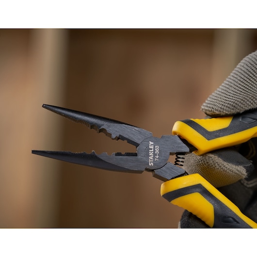 STANLEY STHT0-74364 pliers with yellow and black handles held in a gloved hand, close-up photography.