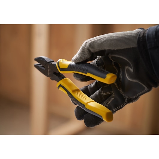 STANLEY STHT0-74454 side cutting pliers with yellow and black handles held by gloved hand, close-up.
