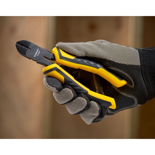 STANLEY STHT0-74455 diagonal cutting pliers with yellow and black handles held in gloved hand.