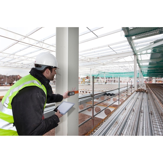 Photo of STANLEY STHT1-77347 laser distance measurer used by worker in construction site photography.