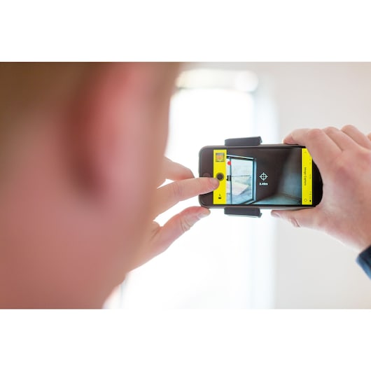 STANLEY STHT1-77366 photography showing a person using a mobile phone to measure a room with yellow app interface