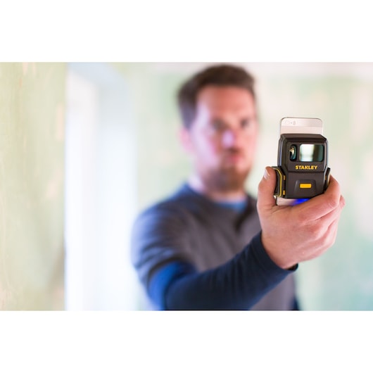 Photography of STANLEY STHT1-77366 laser measuring tool held in hand in indoor setting