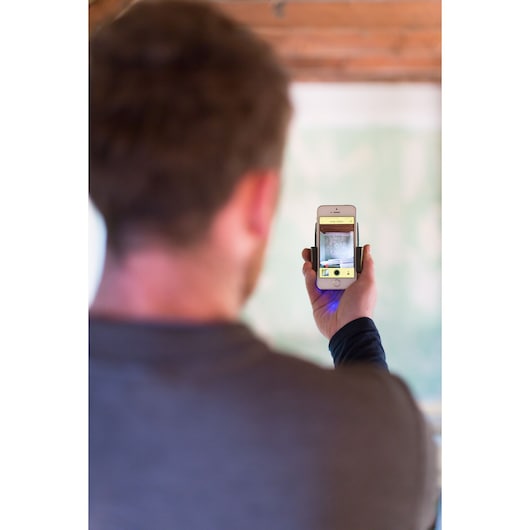 STANLEY STHT1-77366 photography device attached to smartphone, held by person in indoor setting.