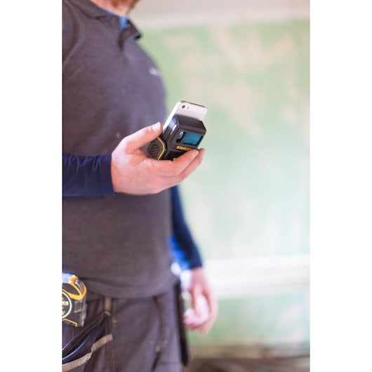 STANLEY STHT1-77366 laser distance measurer held by person, indoor setting, close-up side view.