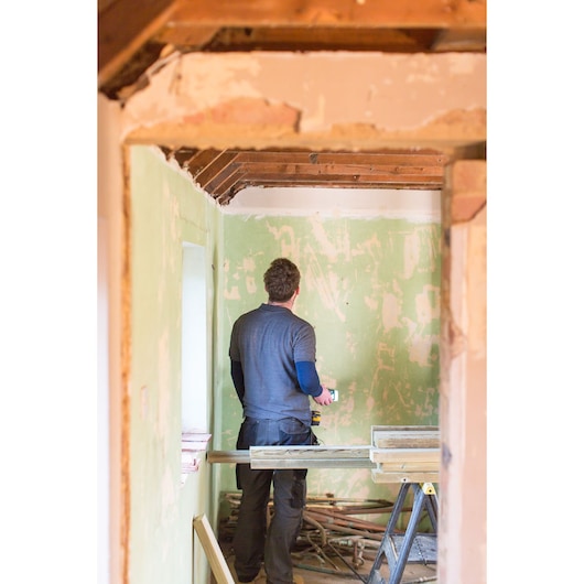 STANLEY STHT1-77366 photography of person using tool in unfinished room with exposed beams.