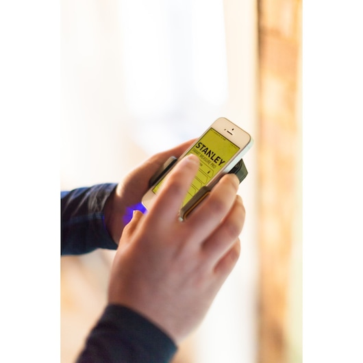 STANLEY STHT1-77366 Photography, person using yellow mobile app screen with handheld device.