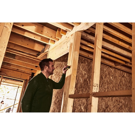 Photo of STANLEY STHT1-77409 laser distance measurer used by a person on a wood framing construction site.