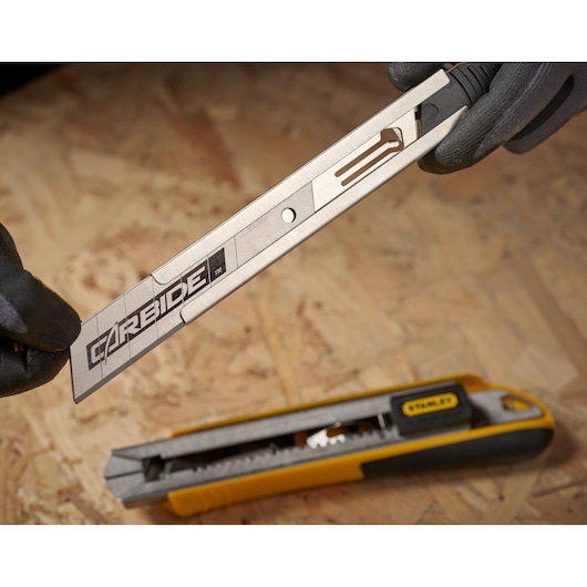 STANLEY STHT3-11825 utility knife with exposed carbide blade on wood surface, close-up angle.