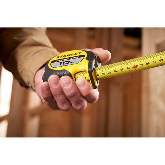 Photo of STANLEY STHT37241 10m tape measure held in hand, yellow and black design, extended measuring blade.