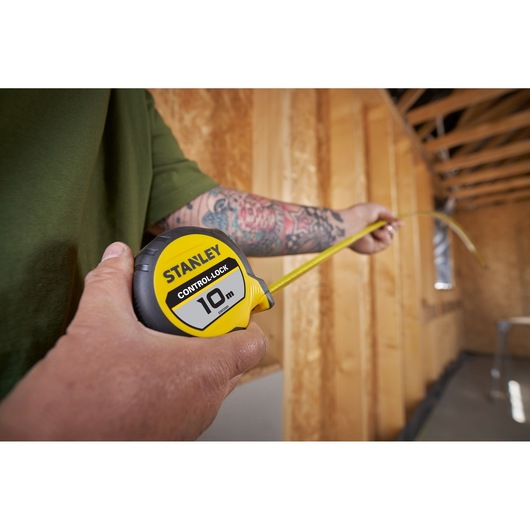 Photo of STANLEY STHT37241 tape measure 10m being used in a wooden construction setting.
