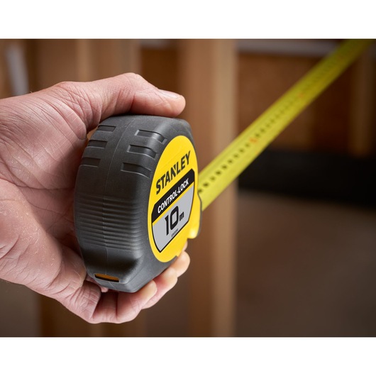 Photo of STANLEY STHT37241 tape measure, yellow and black, 10m, being held by hand and fully extended.