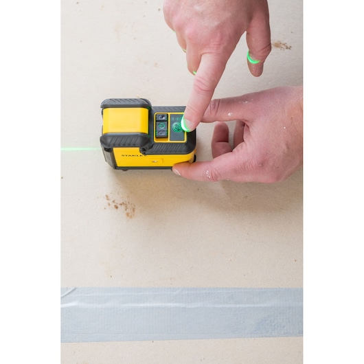 Photo of STANLEY STHT77641-1 laser level being operated by hand on a flat surface.