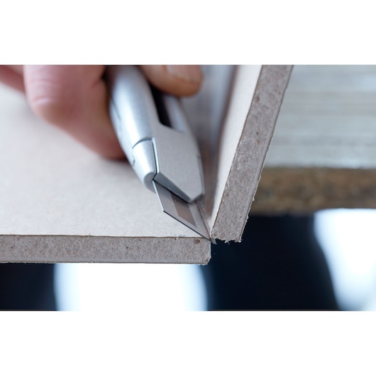 STANLEY STHT8-11818 utility knife cutting drywall, close-up side angle photography.