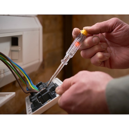 Photo of STANLEY XTHT0-62692 voltage tester screwdriver used on electrical wiring, close-up view.