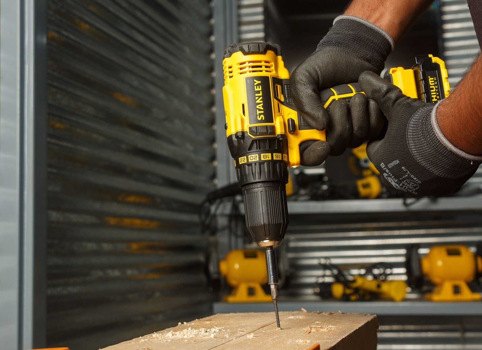 Stanley SCD20C2K cordless drill in use drilling into wood, close-up, yellow and black tool.